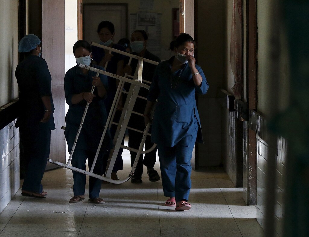 Health workers carry a hospital bed out of the maternity hospital which was damaged by the April 25 earthquake and is no longer in use in Kathmandu, Nepal, May 7, 2015. REUTERS/Olivia Harris