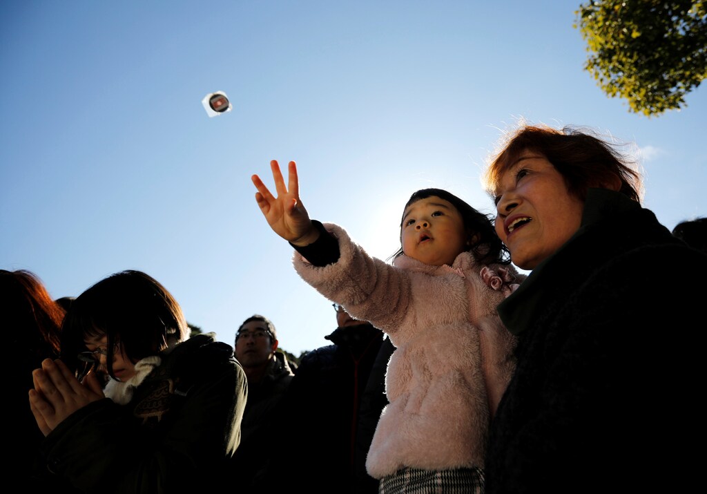 A girl throws a coin as she offers prayers with her family members on the first day of the new year at the Meiji Shrine in Tokyo, Japan, January 1, 2020. REUTERS/Issei Kato - RC2S6E9FHJ66