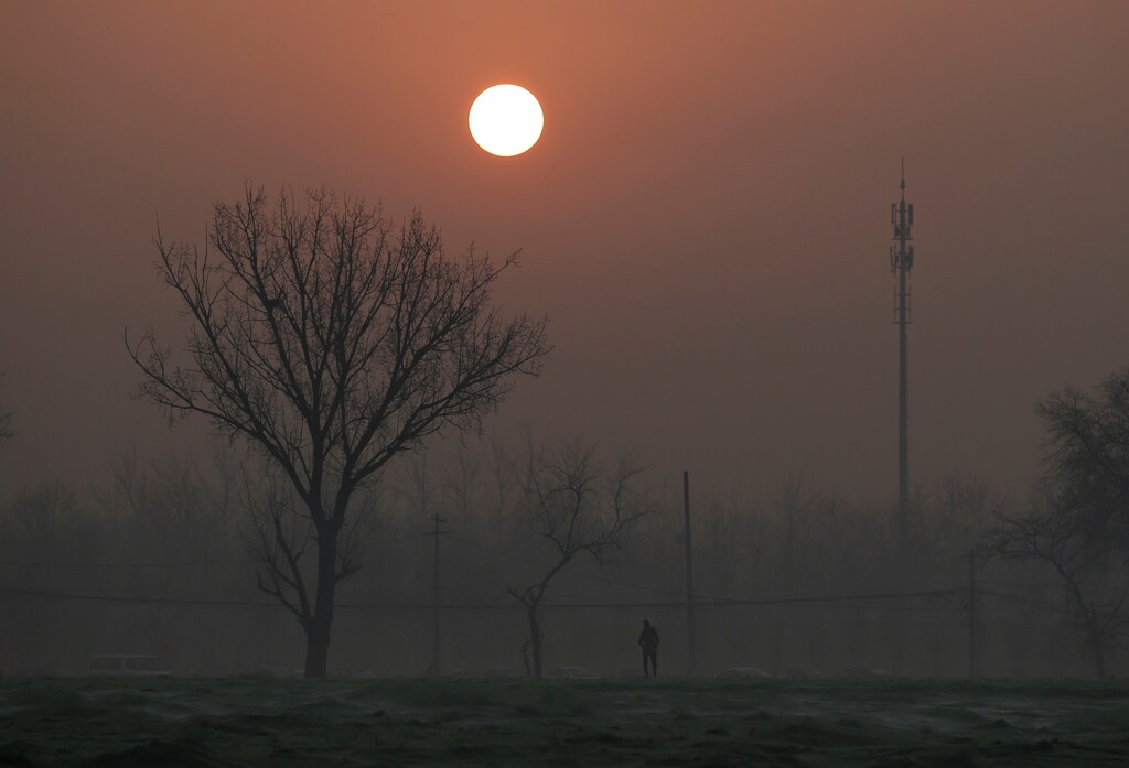A man walks during sunrise in smog on a polluted day as a red alert issued for air pollution in Beijing, China, December 19, 2016. REUTERS/Jason Lee - RTX2VLHZ
