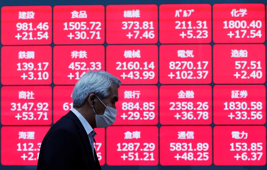 A man wearing a protective face mask walks past a stock quotation board outside a brokerage, amid the coronavirus disease (COVID-19) outbreak, in Tokyo, Japan November 2, 2020.