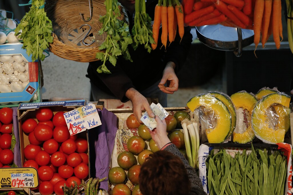 A costumer pays her shopping in a fruits and vegetables shop at a food market in the Andalusian capital of Seville, southern Spain March 7, 2016. REUTERS/Marcelo del Pozo - RTS9NYV