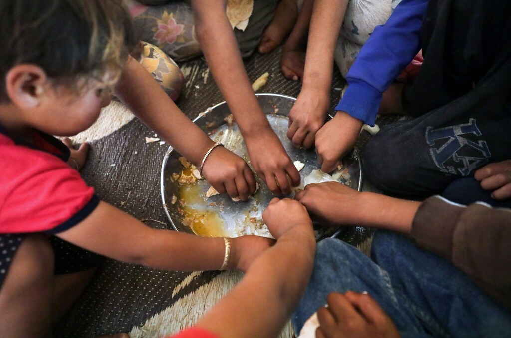 Ahmad Yassin al-Ali and Fawza Umri's children eat together inside their tent, at Atmeh camp, near the Turkish border, Syria June 13, 2020. Picture taken June 13, 2020.