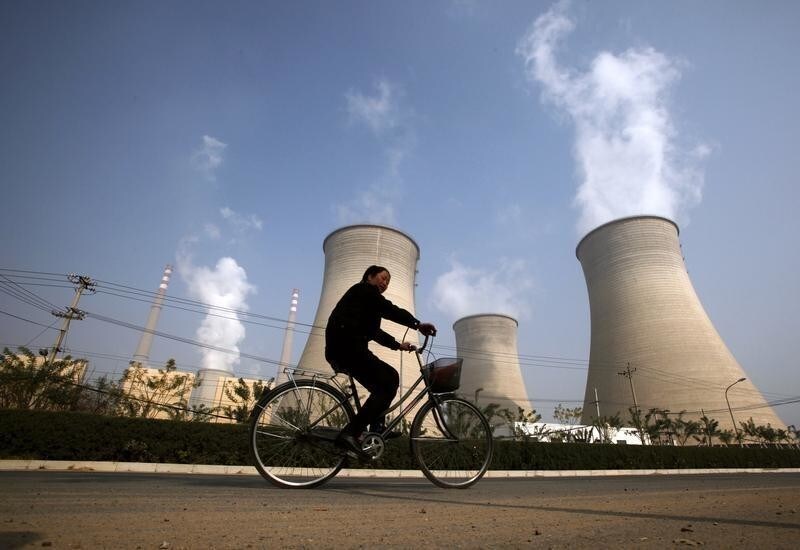 A woman rides her bicycle past the chimneys of a power station located on the outskirts of Beijing October 29, 2009. China is on track to build its first commercial-scale power plant that can capture and store emissions, but experts say it must speed up research on where and how to sequester carbon. China is the world's biggest emitter of the greenhouse gasses that cause global warming and is under increasing pressure to agree to curb output. But coal is China's most plentiful domestic source of energy, and the government hopes for decades of rapid economic expansion to lift millions more from poverty, so capturing and storing carbon dioxide is likely to be crucial to any reduction. REUTERS/David Gray (CHINA ENVIRONMENT POLITICS) - GM1E5AT114P01
