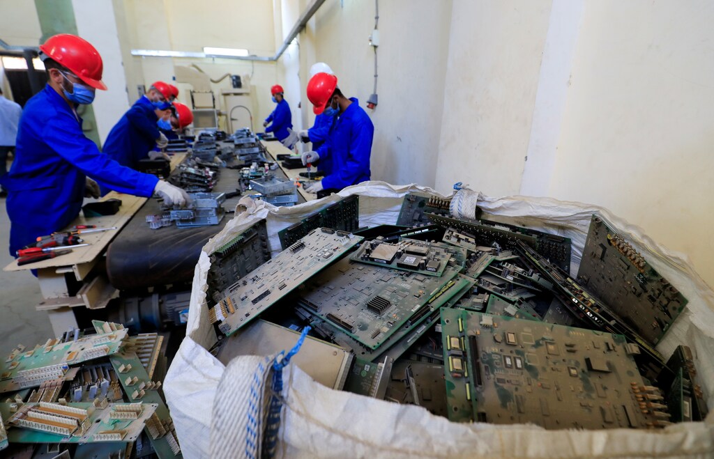 Factory employees working with electronic parts (e-waste) to be recycled into pieces of gold, silver and other precious metals