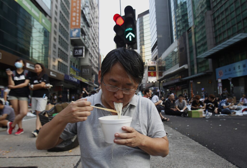 A protester eats noodles in the middle of a main road occupied by protesters, at Mongkok shopping district in Hong Kong September 30, 2014. Tens of thousands of pro-democracy protesters extended a blockade of Hong Kong streets on Tuesday, stockpiling supplies and erecting makeshift barricades ahead of what some fear may be a push by police to clear the roads before Chinese National Day. REUTERS/Liau Chung-ren (CHINA - Tags: POLITICS CIVIL UNREST) - RTR48B5L