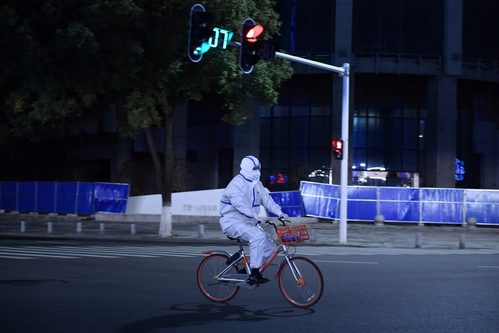 A man in a protective suit rides a shared bicycle at an intersection in Wuhan, the epicentre of the novel coronavirus outbreak, Hubei province, China March 4, 2020. REUTERS/Stringer CHINA OUT - RC22DF9GAY33