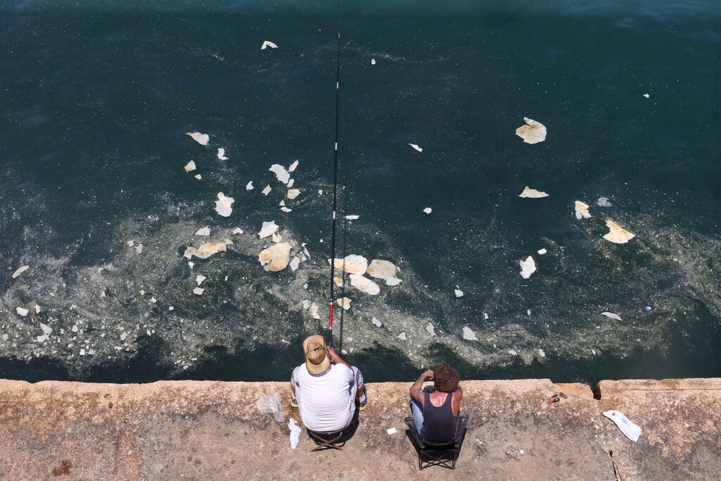 A fisherman dangles his line to catch fish in polluted water off Beirut's seaside Corniche, Lebanon June 23, 2019. REUTERS/Mohamed Azakir - RC14D8253860