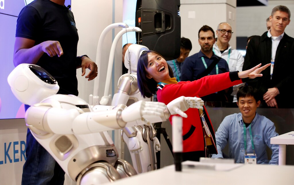 a woman laughs while mimicking a robot with people looking on fondly