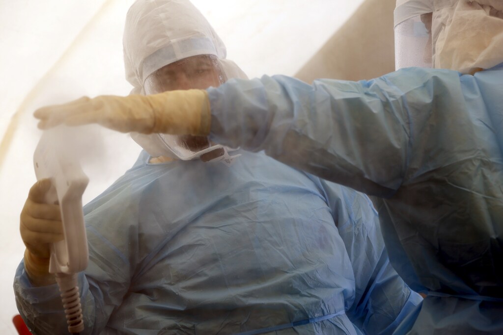 Health workers in hazmat suits decontaminate each other inside a decontamination tent after handling a simulated patient with suspected Ebola while taking part in a training exercise at Malta International Airport outside Valletta April 14, 2015. Emergency and medical personnel on Tuesday held an exercise at the airport to test their response should any patient with a highly infectious disease arrive in the country, according to local media.REUTERS/Darrin Zammit Lupi MALTA OUT. NO COMMERCIAL OR EDITORIAL SALES IN MALTA - GF10000058920