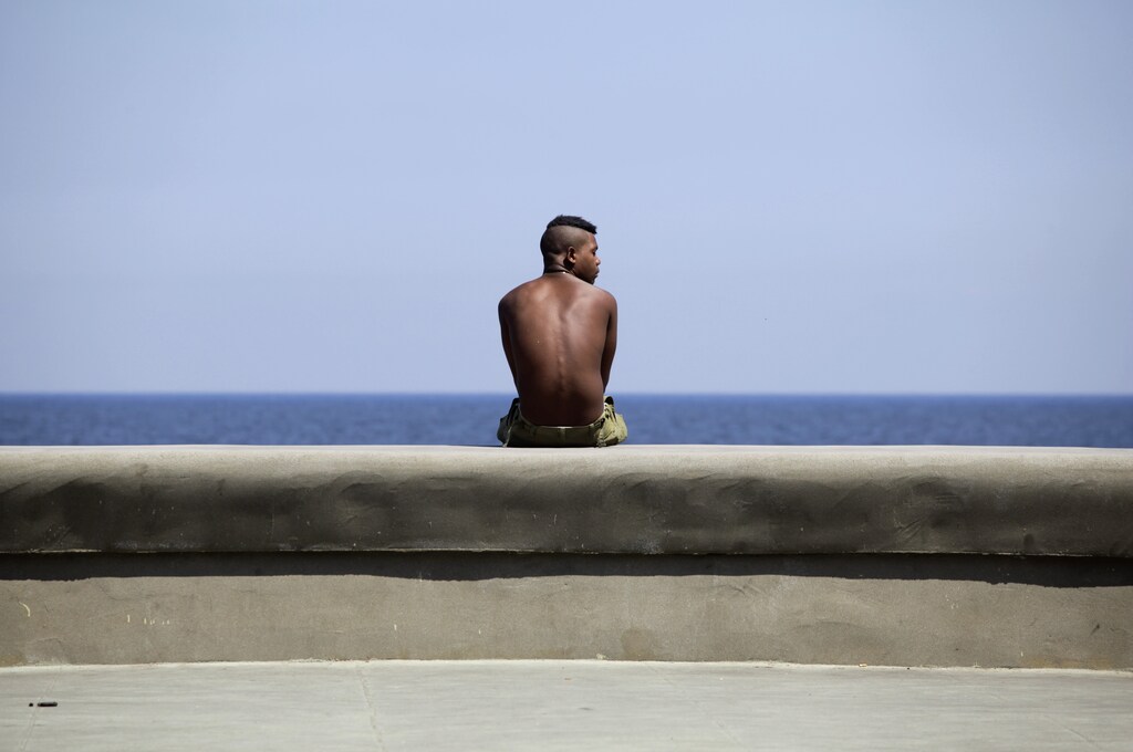 A youth sits on Havana's seafront boulevard 'El Malecon' May 21, 2013. REUTERS/Desmond Boylan (CUBA - Tags: SOCIETY) - GM1E95M09CE01
