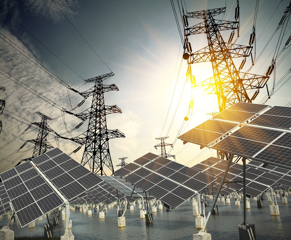 Paneles solares junto a torres de energía eléctrica. La electrificación y la eficiencia son dos pilares clave necesarios para hacer realidad las emisiones netas cero.