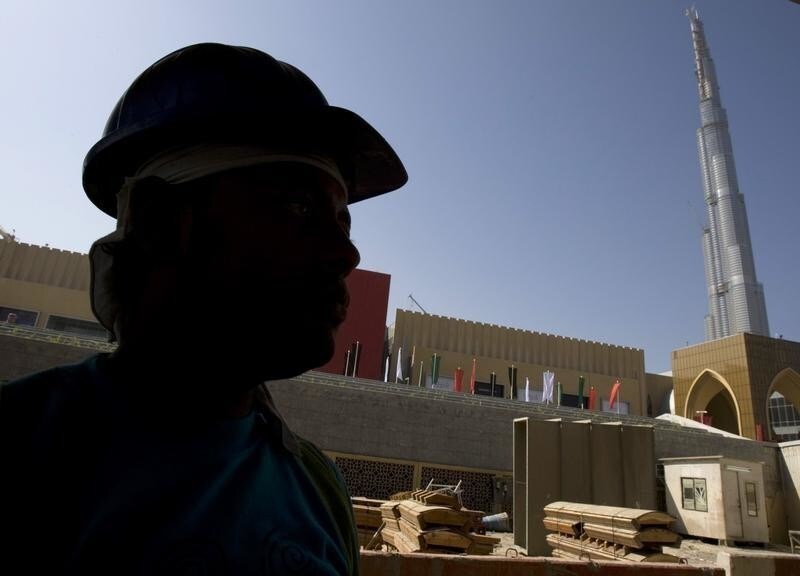 A worker is silhouetted as Burj Dubai, the tallest tower in the world, is seen in the background at a construction site near Burj Dubai Mall, October 29, 2008. The Dubai Mall, one of the world's largest, has pushed back its opening on October 30 to five days later. REUTERS/Ahmed Jadallah (UNITED ARAB EMIRATES) - RTXA15G