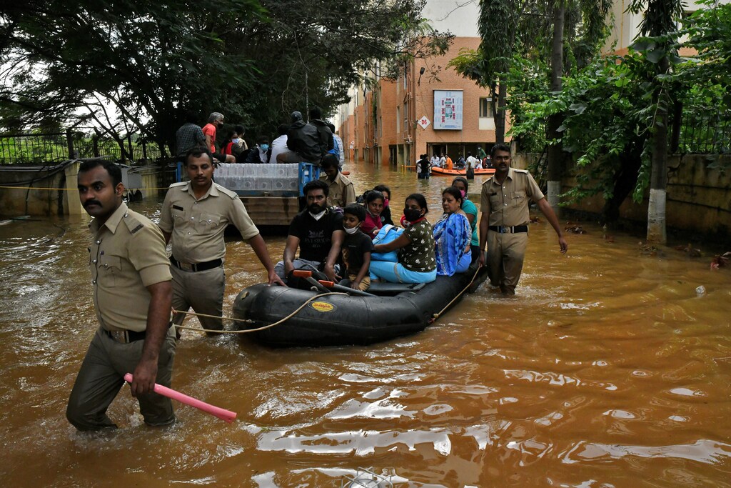 A dinghy-full of people is guided through flooded streets in India.