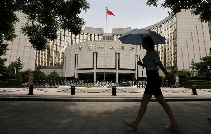 A woman walks past the headquarters of the People's Bank of China (PBOC), the central bank, in Beijing, June 21, 2013.