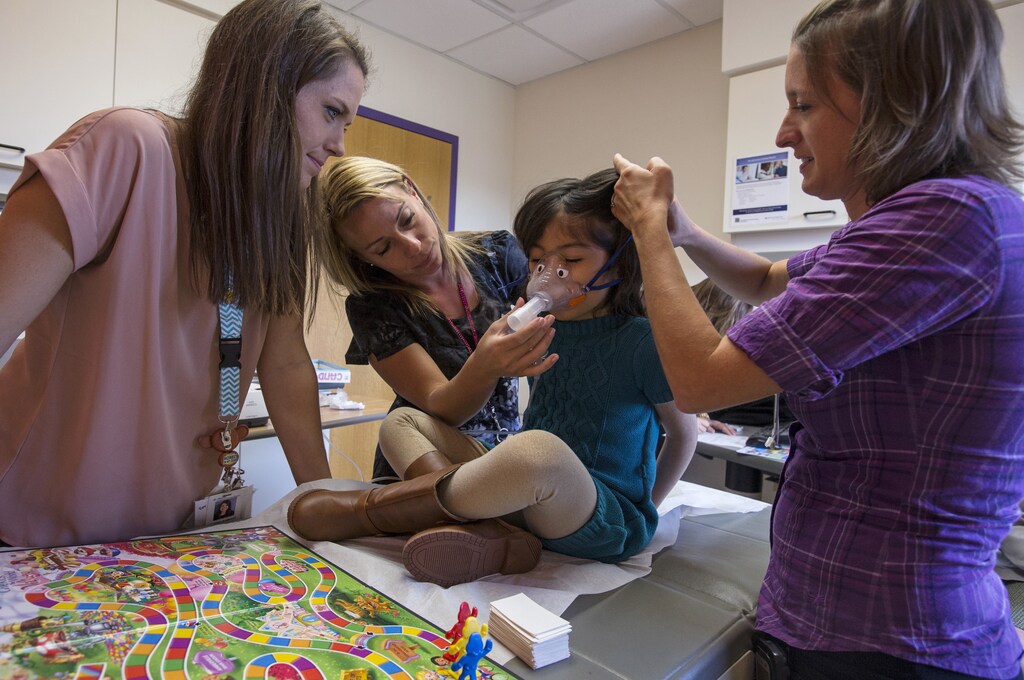 Advocate Children's Hospital staff members Katelyn Anderson (L), Ann Marie Anzalone (2nd L) and Kevynne Chawle (R) help Sophia Trujillo with a nebulizer treatment at Advocate Children's Hospital in Park Ridge, Illinois, September 25, 2015. Trujillo has aplastic anemia and needs a bone marrow transplant but with her multi-racial background of Filipino, Spanish, Irish and Italian, the search for her match has been difficult. REUTERS/Jim Young - RTX1SJ28