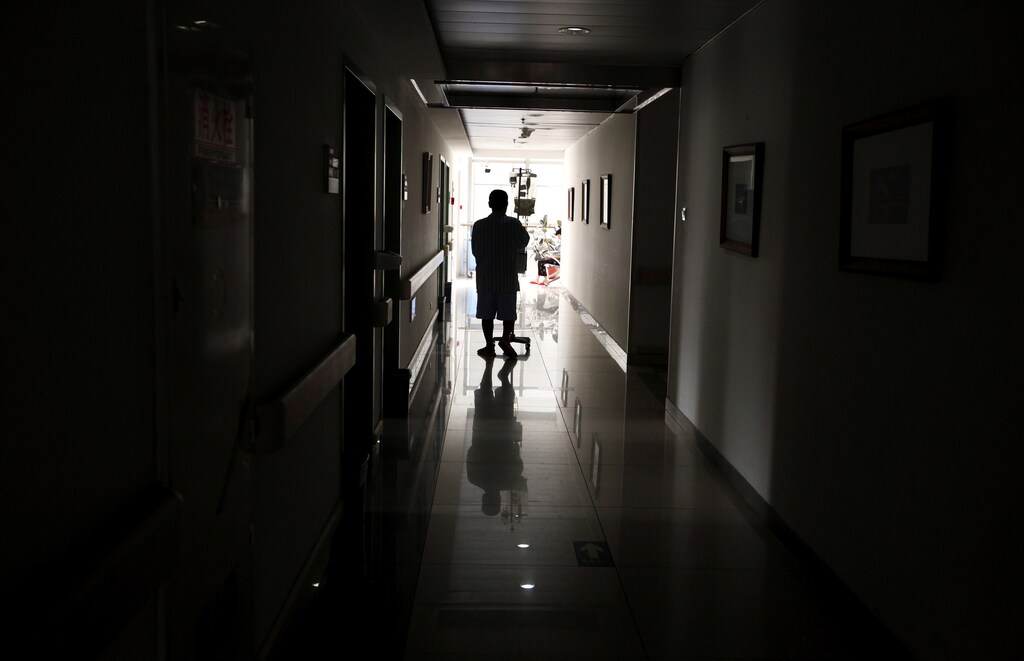 A cancer patient pushes his drip stand as he walks down the hallway of a hospital in Beijing, China July 12, 2011. REUTERS/David Gray/File Photo - S1AETORWYLAA