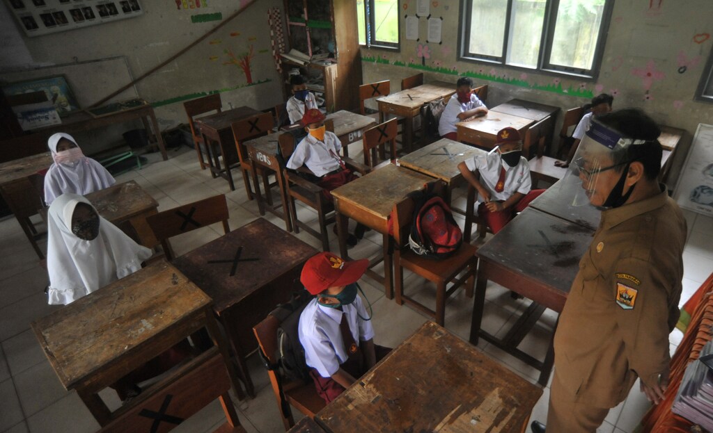 Students and teacher wear protective face masks and shields after Indonesian government reopened schools by implementing face-to-face learning process amid the coronavirus disease (COVID-19) outbreak in Pariaman, West Sumatra Province, Indonesia July 13, 2020, in this photo taken by Antara Foto/Iggoy el Fitra/via Reuters. ATTENTION EDITORS - THIS IMAGE WAS PROVIDED BY THIRD PARTY. MANDATORY CREDIT. INDONESIA OUT. - RC2ESH9TVKVR