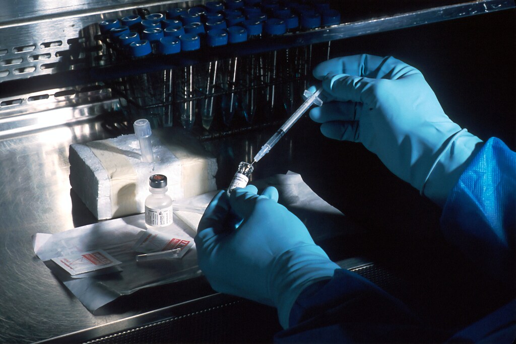 A medical professional transferring liquid into a vial.