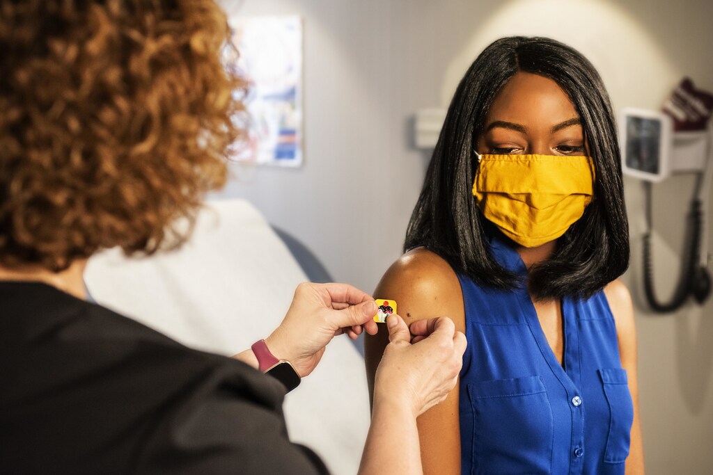This image shows a lady receiving a vaccination, illustrating how multiple factors must combine to reach health equity