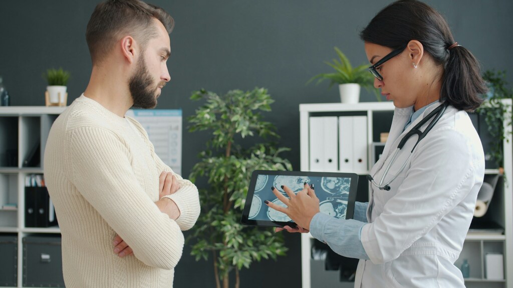 Médico y paciente observan una tableta con escáneres cerebrales; salud resiliente al clima