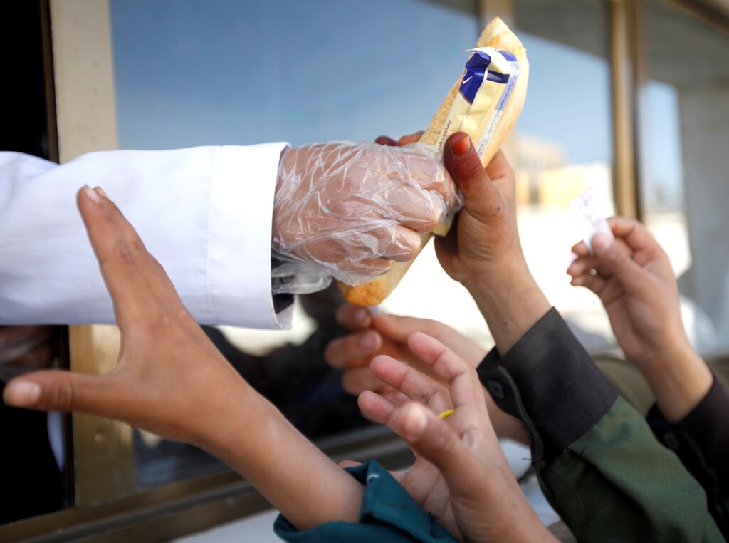Students gather in front of a window to get breakfast, which is distributed free of charge at a school in Sanaa, Yemen February 19, 2019.REUTERS/Mohamed al-Sayaghi - RC199C3F6FD0