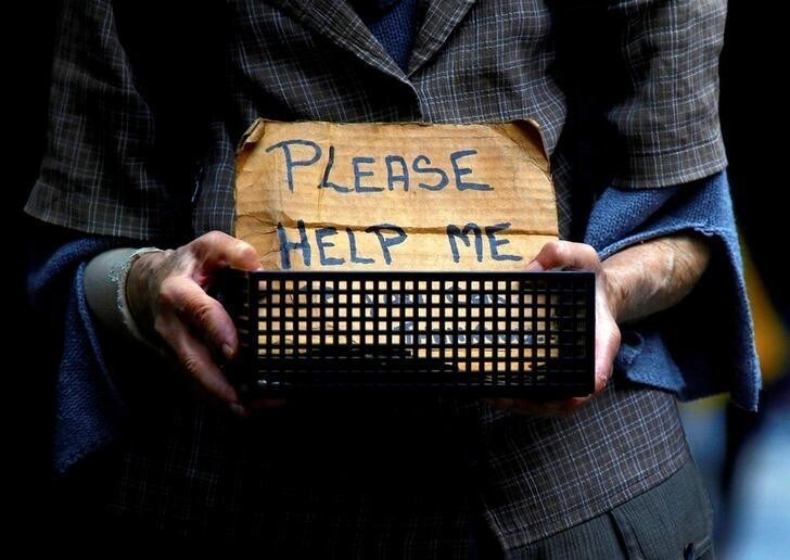 A woman claiming to be homeless holds a container bearing a sign reading "Please Help Me" as she begs for money on a footpath in central Sydney, Australia, October 28, 2016. REUTERS/David Gray