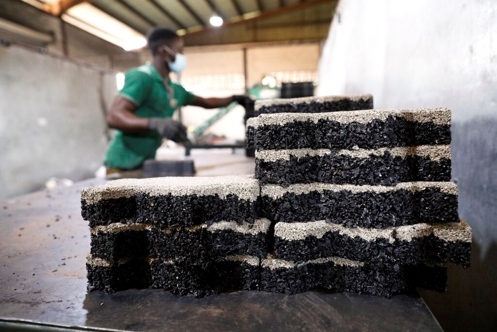 A man arranges newly moulded rubber interlocking tiles manufactured from recycled car tyres at the Freetown waste management recycle factory in Ibadan, Nigeria. REUTERS/Temilade Adelaja