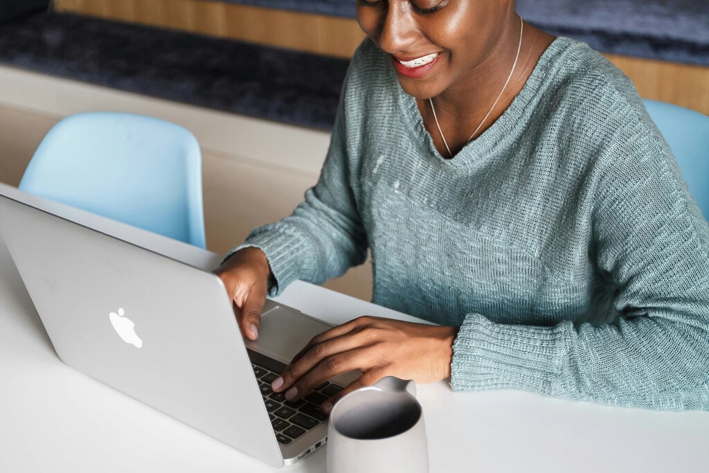 A woman in a blue/green jumper using a laptop. Recruitment