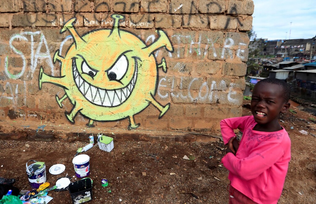 A child stands next to an advocacy graffiti by the Mathare Roots's youth group against the spread of the coronavirus disease (COVID-19), at the Mathare Valley slum, in Nairobi, Kenya April 19, 2020. Picture taken April 19, 2020. REUTERS/Thomas Mukoya - RC2CAG91OLDA
