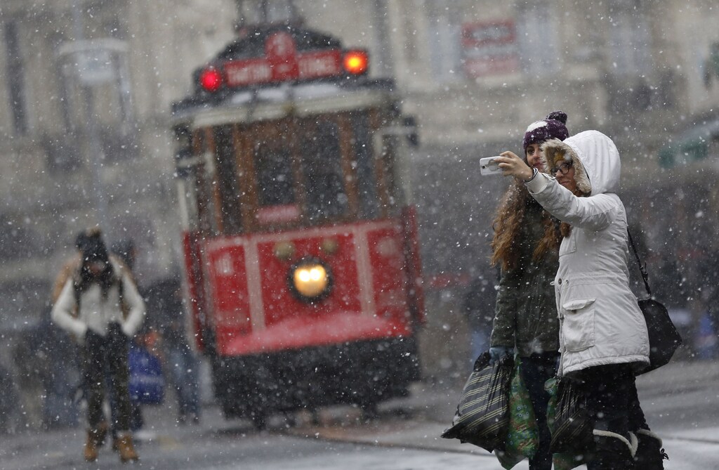 Pedestrians, with a vintage tram in the background, take a "selfie" as snow falls at the main shopping street of Istiklal in central Istanbul January 6, 2015. REUTERS/Murad Sezer (TURKEY - Tags: ENVIRONMENT SOCIETY) - GM1EB1702Y101