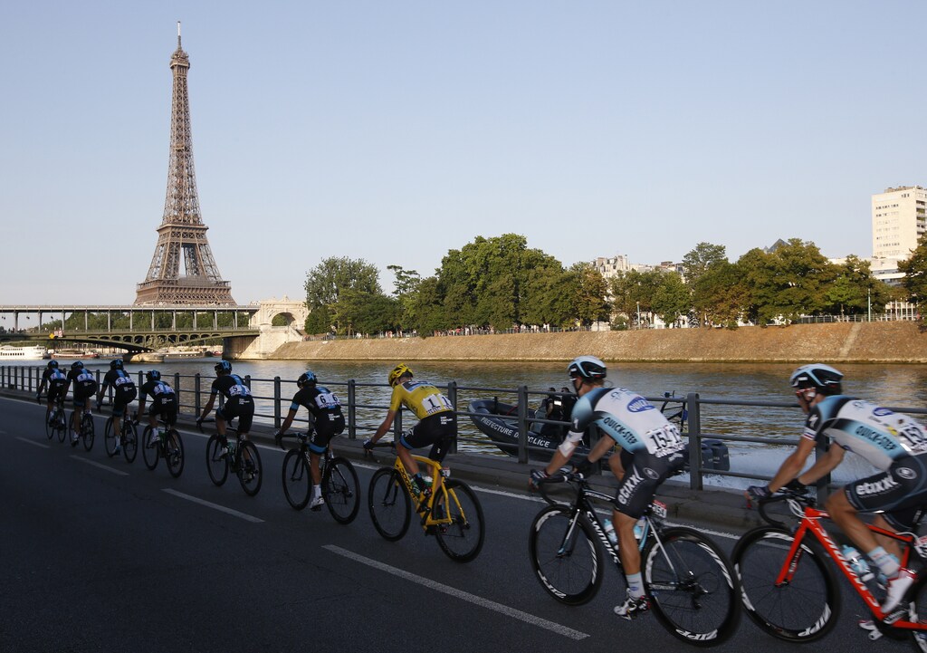 The pack of riders including Team Sky rider and leader's yellow jersey holder Christopher Froome of Britain cycle on the banks of the Seine river past the Eiffel Tower during the 133.5km final stage of the centenary Tour de France cycling race from Versailles to Paris Champs Elysees, July 21, 2013. REUTERS/Eric Gaillard (FRANCE - Tags: SPORT CYCLING) - LR2E97L1G3XY7