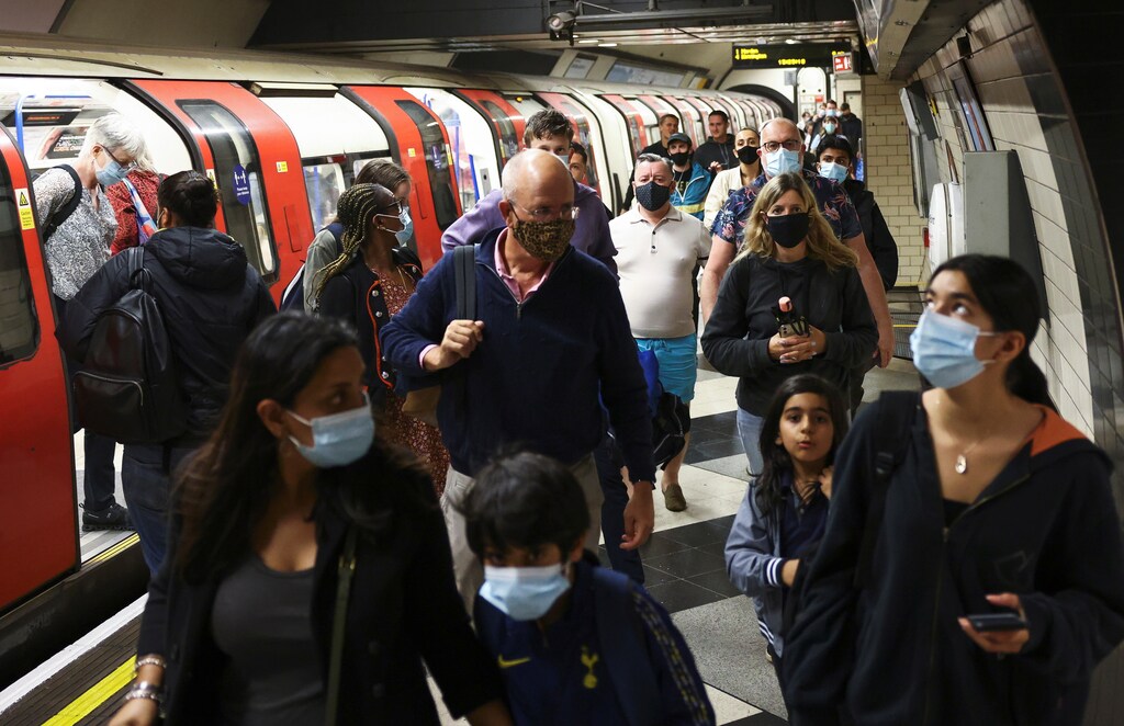 People wearing protective face masks walk along a platform on the London Underground,