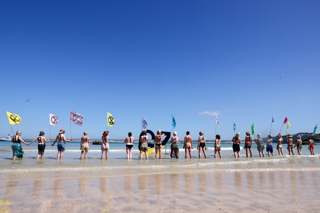 Extinction Rebellion demonstrators stand with the quote 'Drowning in promises' written on their backs, in a protest at the beach in St Ives, during the G7 summit, in Cornwall, Britain, June 13, 2021. REUTERS/Tom Nicholson - RC2QZN9EJU1G