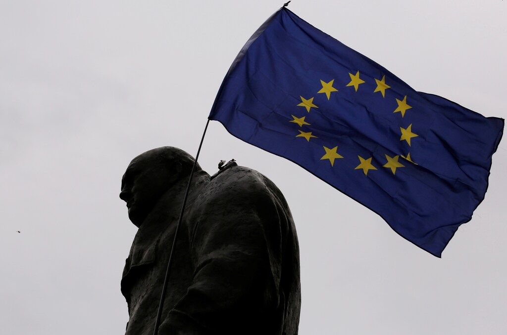A European Union flag is waved over a statue of former Prime Minister Winston Churchill as demonstrators protest during a "March for Europe" against the Brexit vote result earlier in the year, in London, Britain, September 3, 2016. REUTERS/Luke MacGregor - RTX2NZT0