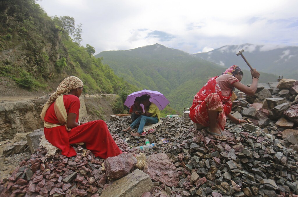 Workers repair a road damaged by a landslide, which was caused by heavy rainfall, as their children listen to songs on a mobile phone in Chamba, in the Himalayan state of Uttarakhand June 26, 2013.