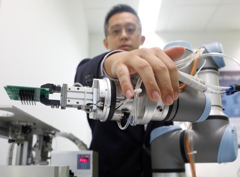 A Universal Robots employee demonstrates how a model of their industrial robot arms works in Singapore March 3, 2017. Picture taken March 3, 2017. REUTERS/Edgar Su - RTS14950