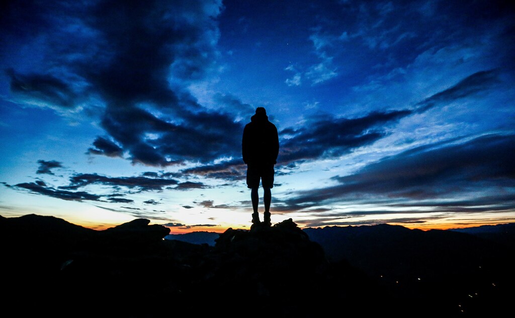 A man stands during sunrise on Kreuzjoch mountain in the Zillertal Alps in Schwendau, Austria July 11 2016. REUTERS/ Dominic Ebenbichler - RTSHD9W