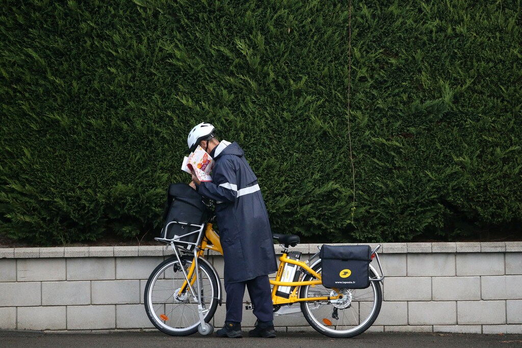A postman of French postal service company La Poste distributes letters using an electrically-assisted bicycle in Vertou, France, September 1, 2017. REUTERS/Stephane Mahe - RC1D3F2A3F00