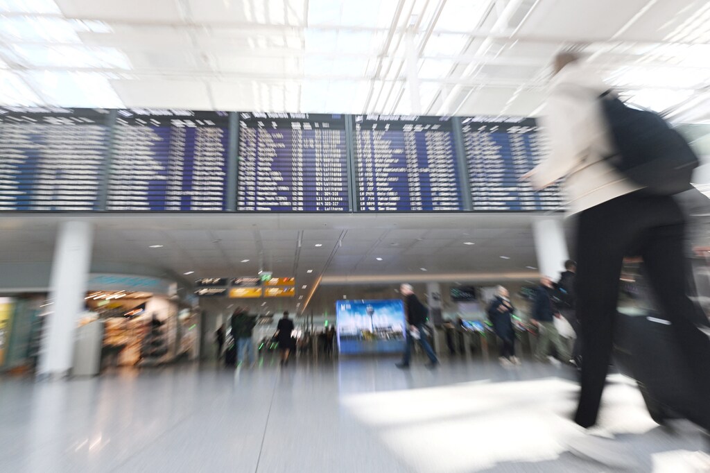 People walk a near display board at the airport in Munich, Germany, October 3, 2025. Munich airport reopened on Friday after shutting overnight due to drone sightings that forced the cancellation or diversion of dozens of flights on the eve of a national holiday and heightened concerns about the vulnerability of critical infrastructure in Europe. Picture taken with a zoom burst. REUTERS/Angelika Warmuth