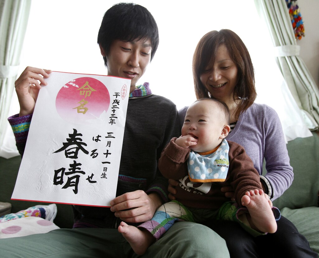 Hiromi Sato holds her son, Haruse, as her husband, Kenji Sato, holds a calligraphy with the characters of his son's name and the date he was born during a photo opportunity at their home in Minamisanriku, northeastern Japan, March 3, 2012. Hiromi gave birth to her son at the Ishinomaki Red Cross hospital on March 11, 2011, the same day when the massive 9.0 magnitude earthquake struck off the northeastern coast of Japan. In a fortunate twist of fate, Kenji Sato, a wiry descendant of fishermen in his coastal hometown of Minamisanriku, took time off from work to see his third child, Haruse, born at a hospital in the nearby port city. A year on, the Satos, who all survived the tsunami since their house was built on a hill, are planning a quiet birthday with some cake and ice cream for the child who, his grandmother Kazuko insists, "was born to save us" Picture taken March 3, 2012. REUTERS/Yuriko Nakao (JAPAN - Tags: DISASTER ANNIVERSARY TPX IMAGES OF THE DAY) - GM1E83611GX01