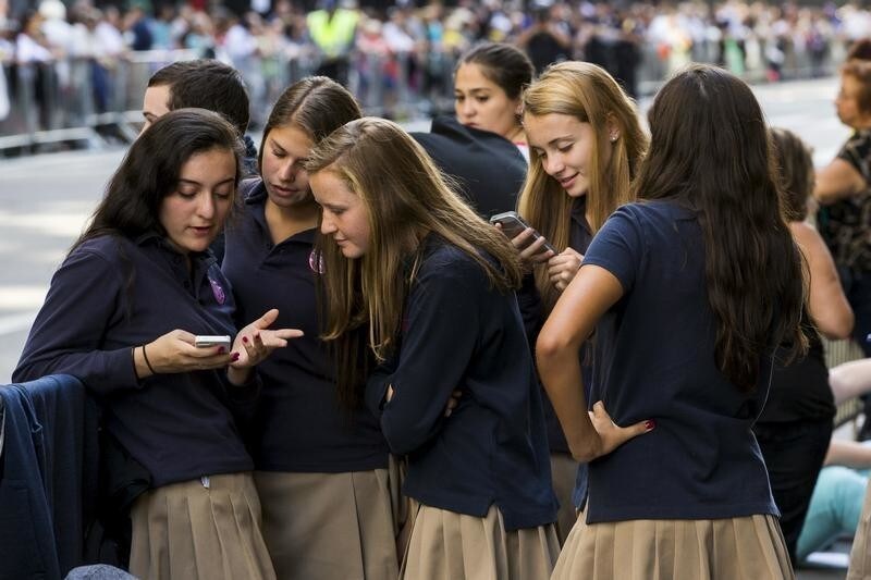 A group of Catholic school girls look at their phones as they wait on the route that Pope Francis will take later in the day near St. Patricks Cathedral in New York September 24, 2015. REUTERS/Lucas Jackson - GF10000219774