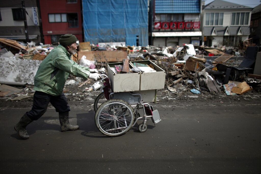 A man pushes a wheelchair with belongings damaged by the tsunami as he clears his house in Kamaishi town, Iwate Prefecture in northern Japan, March 25, 2011. Two weeks after a devastating earthquake and tsunami that obliterated towns on Japan's northeast coast, survivors tried to find sense of normalcy in lives that have been ripped apart. Shelters receive regular food deliveries and visits by medical professionals while an evacuee centre set up in the Buddhist Sekiozenji temple off a main street in Kamaishi is empty during the day as people leave to visit relief offices or try to fix what is left of damaged homes. REUTERS/Carlos Barria