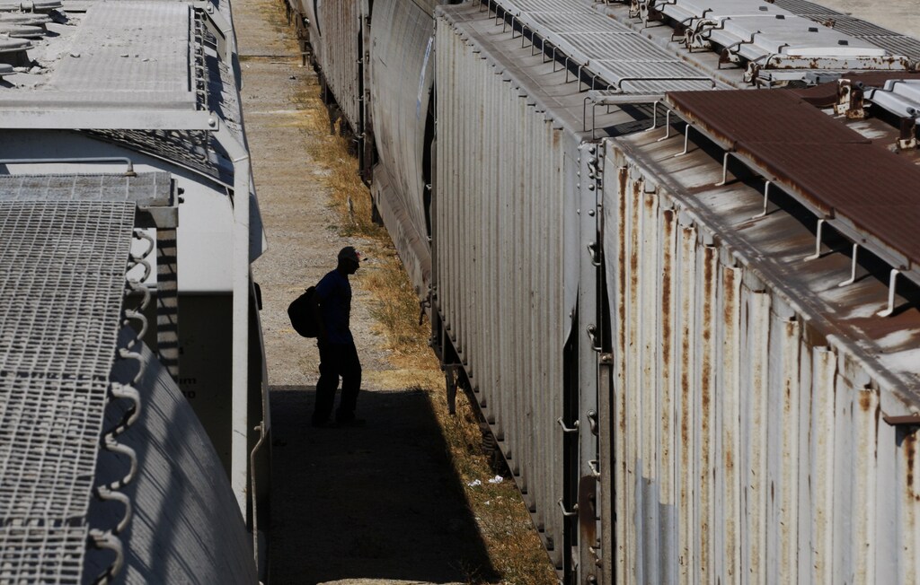 A Central American migrant walks between trains while waiting for the freight train "La Bestia", or the Beast, to travel to north Mexico to reach and cross the U.S. border, at Arriaga, in the state of Chiapas January 10, 2012. Hundreds of thousands of migrants, mostly Central Americans, risk robbery, death from fast-moving freight trains or dehydration in the desert while trying to reach the U.S illegally. REUTERS/Jorge Luis Plata (MEXICO - Tags: TRANSPORT SOCIETY IMMIGRATION) - RTR2W4OQ