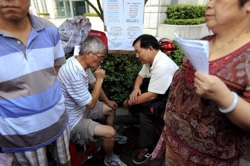 Wu Linan (2nd, L) advices an investor on current trends in China's stock market during a street stock salon in central Shanghai, China, August 29, 2015. Wu, seeing himself as a senior player in stock investment, believes and advises others that the Chinese Communist Party will save the stock market and make people rich. For at least a decade, an area next to the Peoples Square temporarily has transformed itself into a "street stock salon" during weekends, with investors from all over Shanghai coming to gather stock information and learn trading skills from others. A few businessmen also make use of the occasion to promote their stock analysis software.