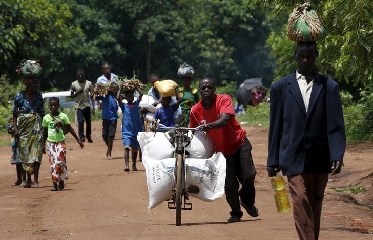 A Malawian man transports food aid distributed by the United Nations World Food Progamme (WFP) through maize fields in Mzumazi village near the capital Lilongwe, February 3, 2016. Late rains in Malawi threaten the staple maize crop and have pushed prices to record highs. About 14 million people face hunger in Southern Africa because of a drought exacerbated by an El Nino weather pattern, according to the WFP. REUTERS/Mike Hutchings