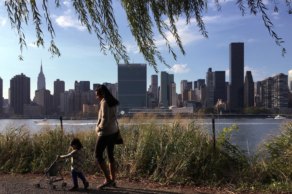A woman and child walk at the Gantry Plaza State Park in the Queens borough of New York with midtown Manhattan including the Empire State Building (L) and the United Nations Headquarters (C) in New York, U.S. October 16, 2016.