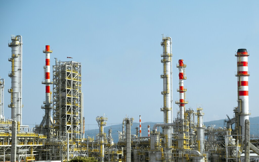 Industrial energy infrastructure with refineries and processing towers, illustrating clean fuels development and the transformation of energy systems.