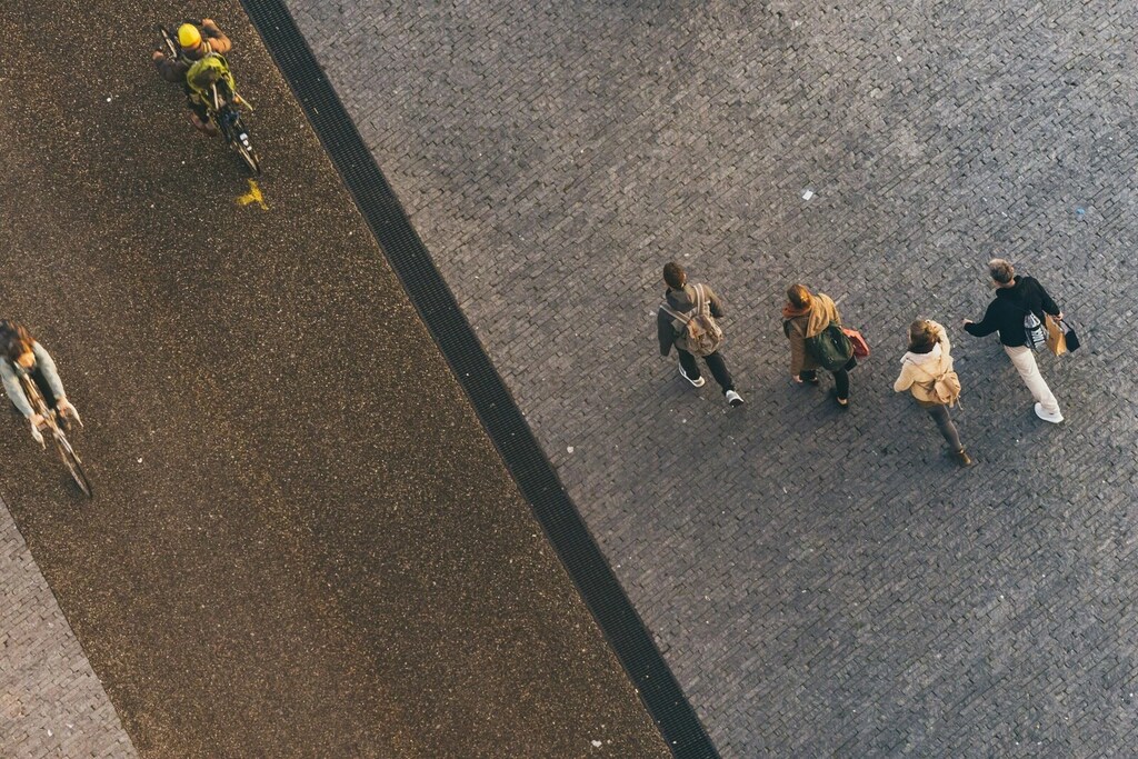 Vista aérea de personas caminando por una calle ancha y en bicicleta por una ciclovía aledaña