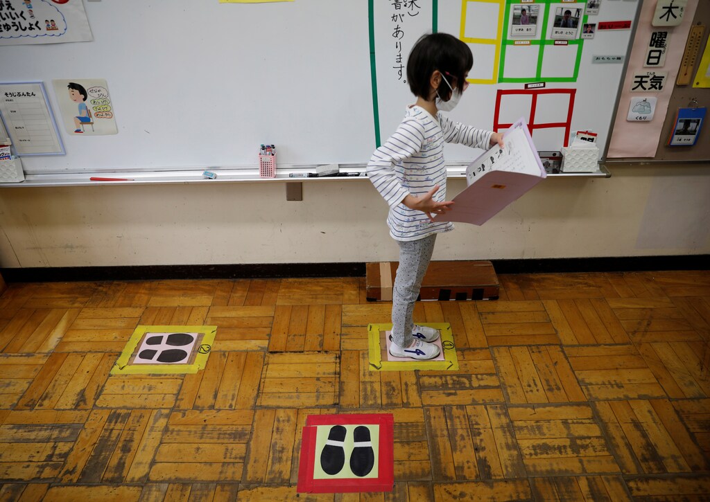 A student wearing a protective face mask amid coronavirus disease (COVID-19) outbreak, stands on a mark for social distancing at a classroom of Takanedai Daisan elementary school, which practices various methods of social distancing in order to prevent the infection, in Funabashi, east of Tokyo, Japan July 16, 2020. REUTERS/Kim Kyung-Hoon - RC27UH9XY06Y