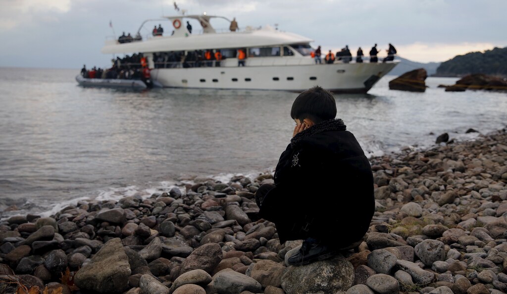A Syrian refugee boy sits on a beach after disembarking from a luxury yacht used by about 250 other Syrian refugees and to travel across the Aegean Sea from the Turkish coast in the Greek island of Lesbos November 21, 2015. REUTERS/Yannis Behrakis